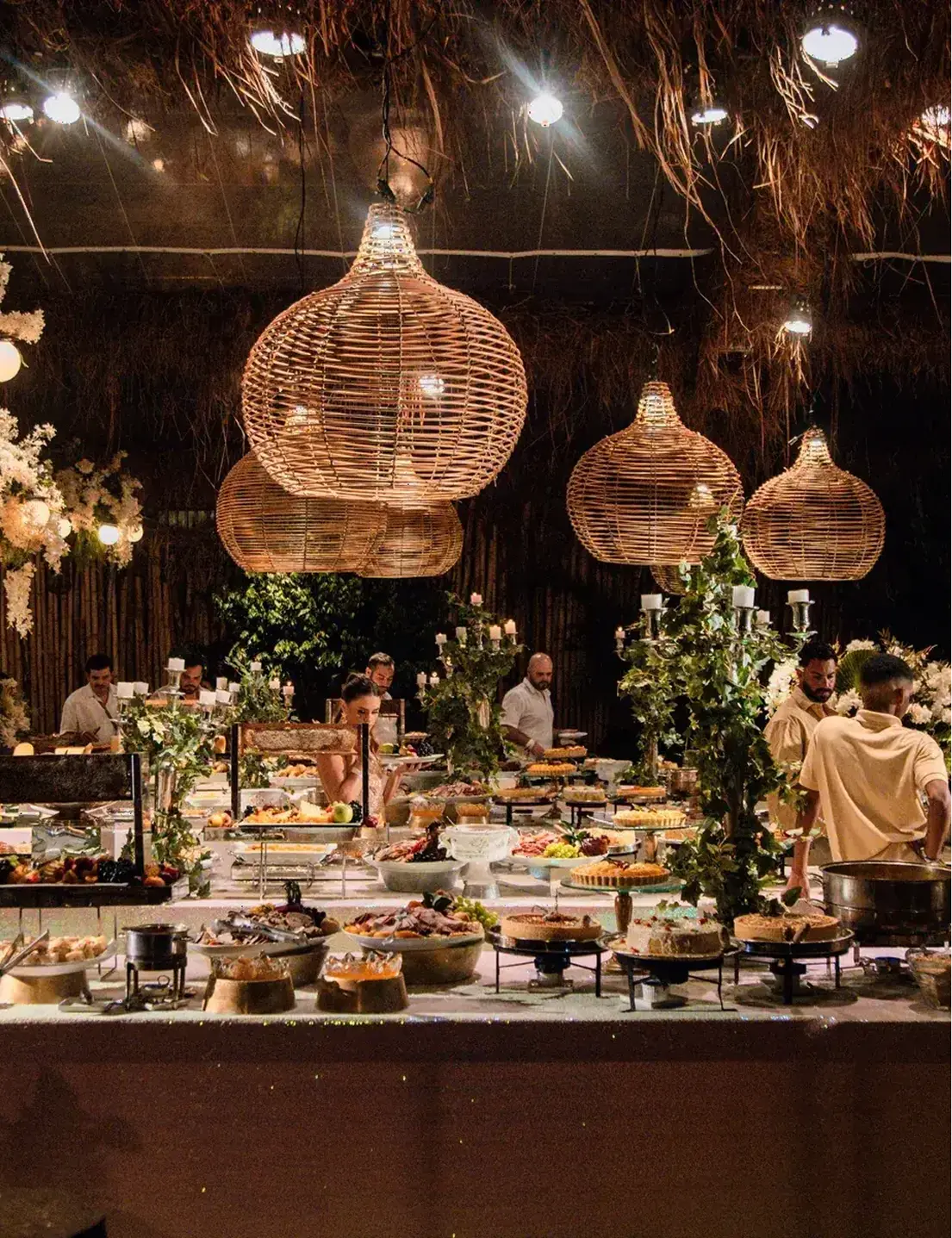 Mesa de banquetes bajo lámparas de mimbre